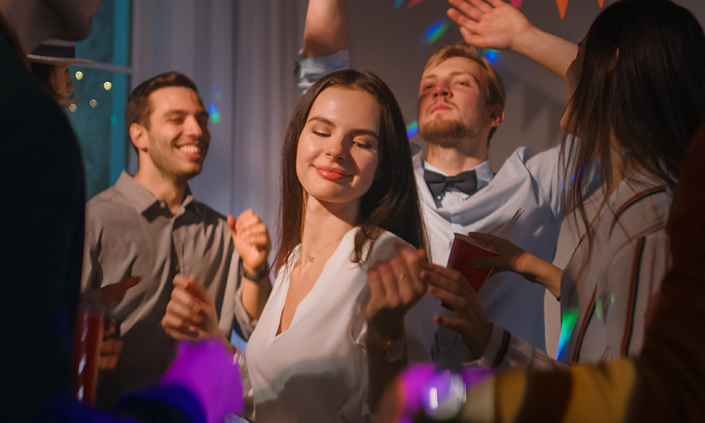 Skupina lidí tancujících na párty, mezi kterými je žena, která si užívá hudbu.